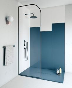 Banheiro com um accent wall que se estende até o chão na cor vintage blue, há também uma ducha preta e alguns itens de banho presentes no ambiente. 